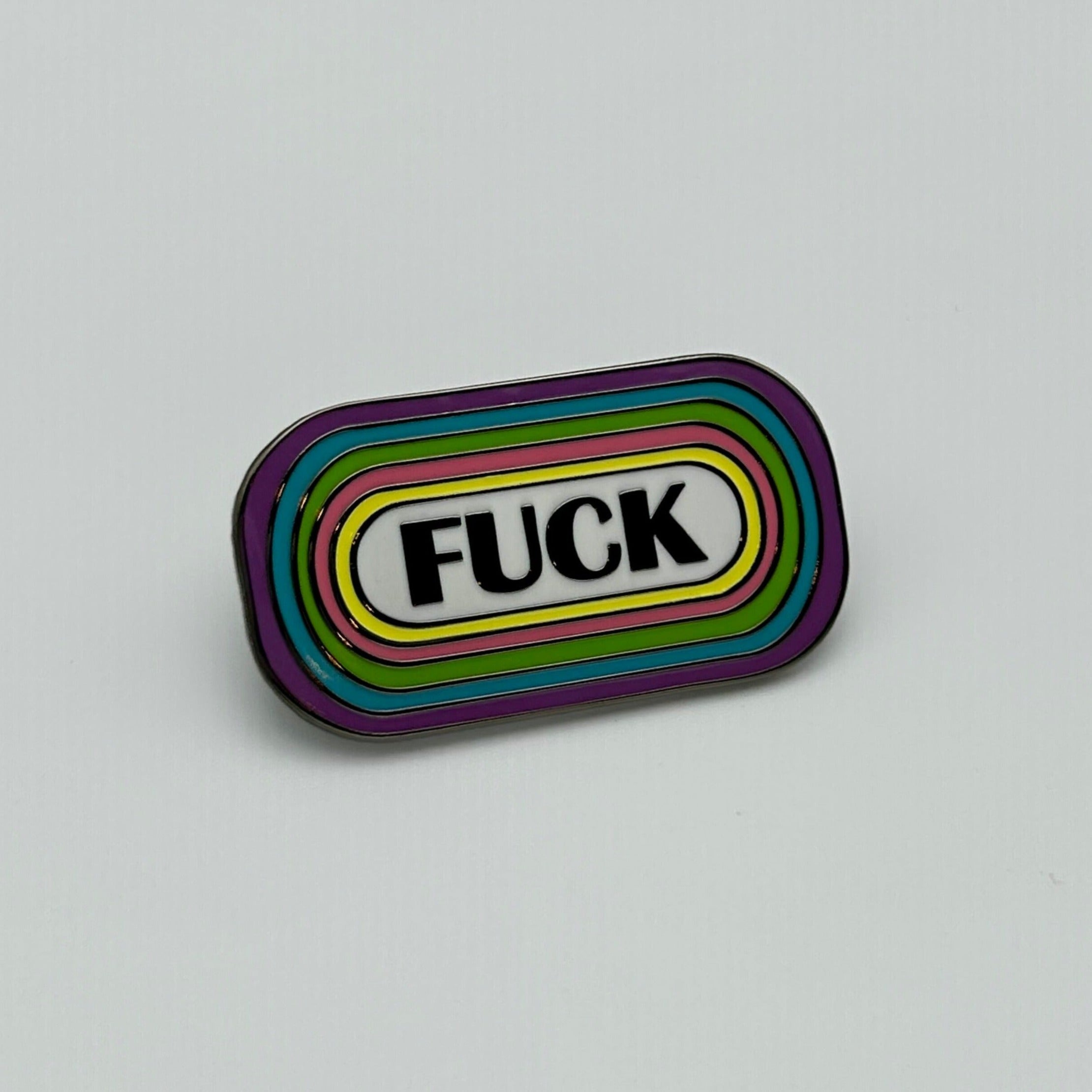 A nickel-plated enamel pin that says "FUCK" in capital lettering. Circling the word is yellow, pink, green, blue, and purple lines.