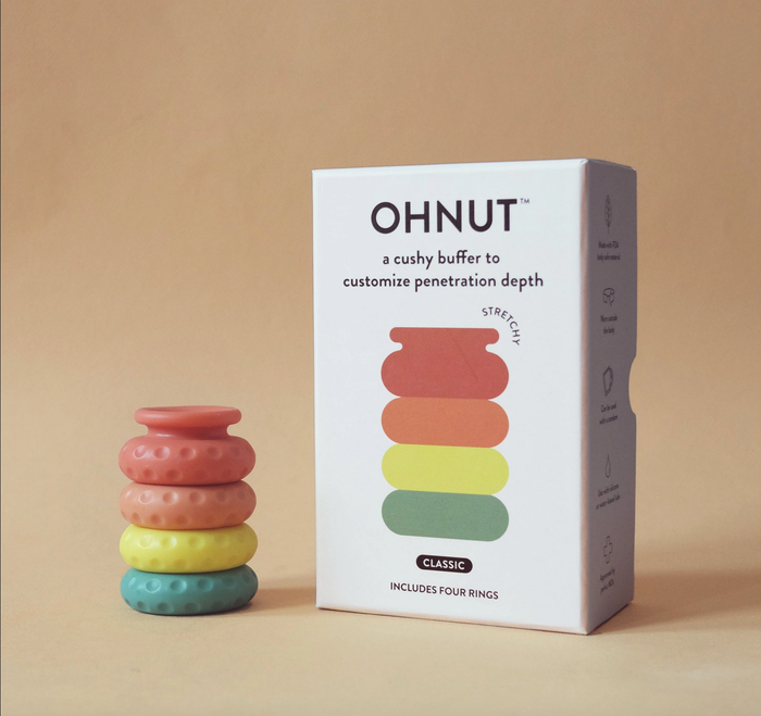 Rainbow ohnut next to it's box. Each ring is a different colour, red, orange, yellow, and green.