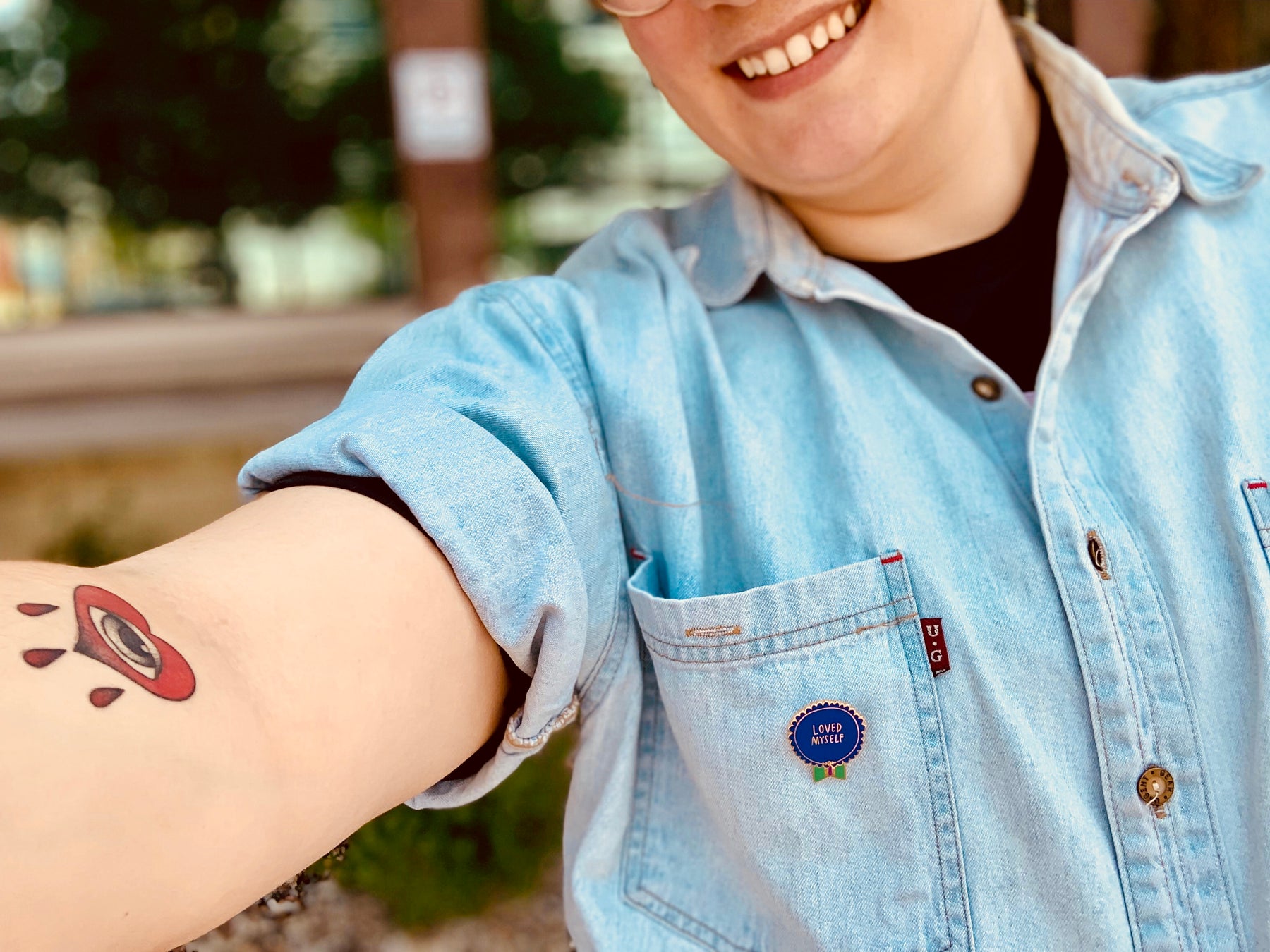 Person wearing a Loved Myself pin on a denim shirt