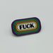 A nickel-plated enamel pin that says "FUCK" in capital lettering. Circling the word is yellow, pink, green, blue, and purple lines.