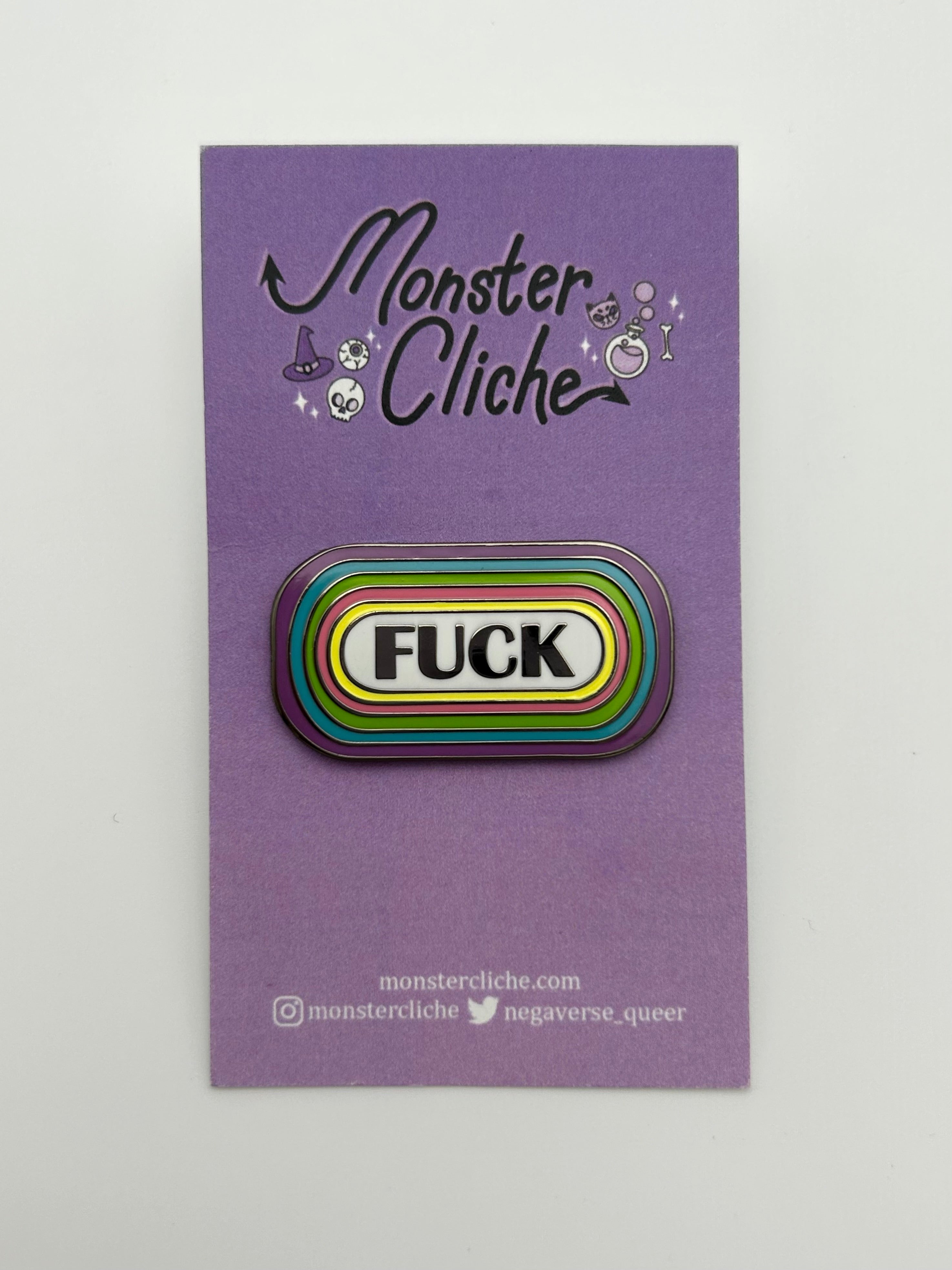 The Fuck pin is attached to the card backing that it comes on, a purple card that says Monster Cliché at the top and the website and social media for the artist at the bottom. Website: monstercliche.com Instagram: @monstercliche Twitter: @megaverse_queer