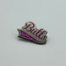 A nickel-plated enamel pin that says Butts in varsity-jacket style font. The end of the letter s continues to underline the entire word. 