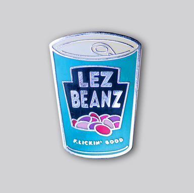 An enamel pin that is shaped like a can of beans. The logo on the can says Lez Beans, and an illustration of baked beans sits under the text. At the bottom of the can are the words "Flickin' good"