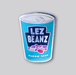 An enamel pin that is shaped like a can of beans. The logo on the can says Lez Beans, and an illustration of baked beans sits under the text. At the bottom of the can are the words "Flickin' good"