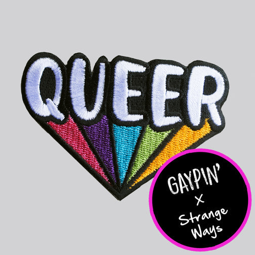 A patch with the word "QUEER" in capital bubble letters. Each letter has a stream of colour under it that join at one point in the middle, creating a rainbow in a triangle shape. 