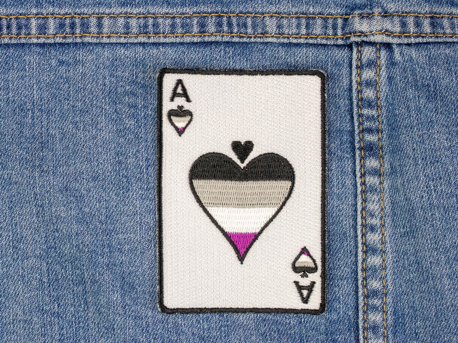 A patch of an Ace of Spades, with the asexual flag colours on the Spade.