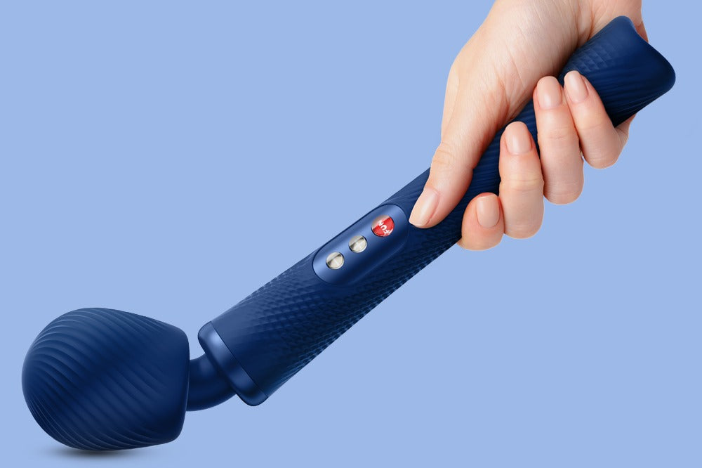 The wand 's head is being pressed into a flat surface to show the flexibility of the neck. It is bending at about a 120 degree angle. A hand is holding it by the base.