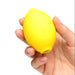 Hand holding a yellow lemon-shaped toy against a white background