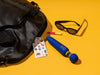 Flip Wand next to a purse, sunglasses and lipstick, on a yellow background