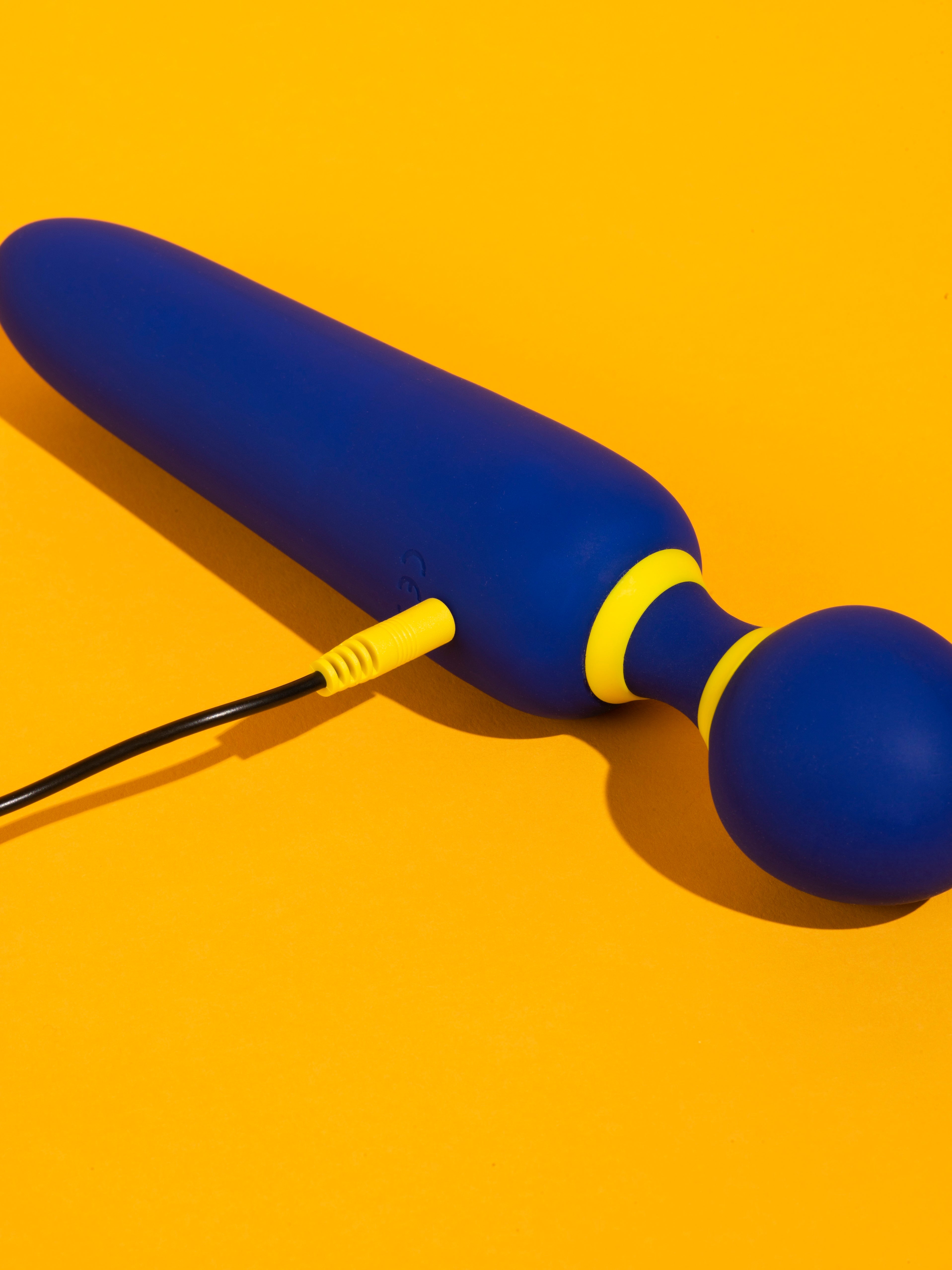 Romp Flip wand on yellow background, plugged in for charging