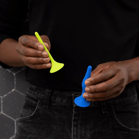 A person holds the smallest and largest sizes of rectal dilators at their waist. The photo is cropped to show just their chest and hips.