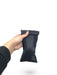 Black packing pouch with packer inside, being held by a hand