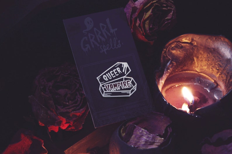 Queer vampire pin on backing by candle